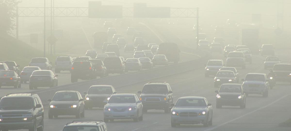 Cars in a haze on a highway.